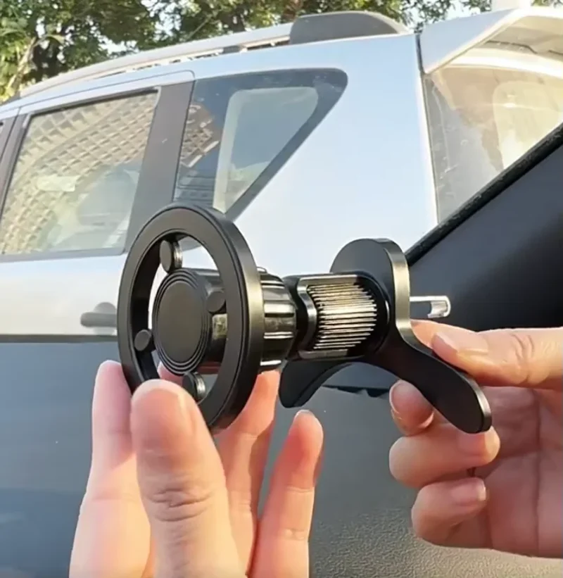 Hand holding strong magnetic air vent car phone holder, showing adjustable air vent clip and 360 rotation joint